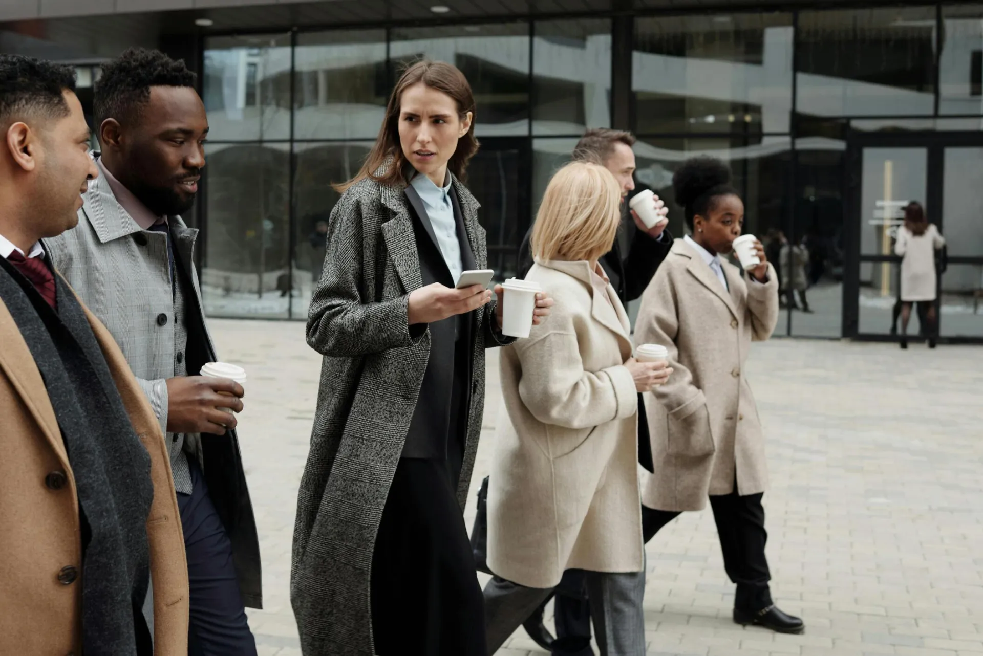 A group of diverse business professionals enjoying a coffee break outdoors in the city.