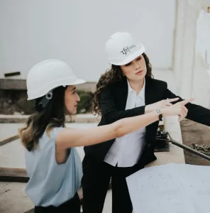Two female architects discussing building plans outdoors, emphasizing teamwork and women leadership.