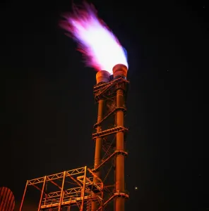Dramatic night photo of gas flare on industrial facility emitting a powerful flame.