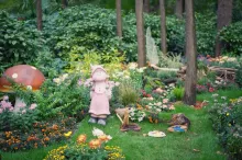 Charming garden scene with a fairy statue, mushroom, and colorful flowers.