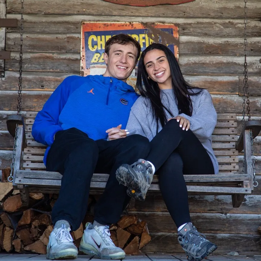 smiling couple sits on a porch swing together