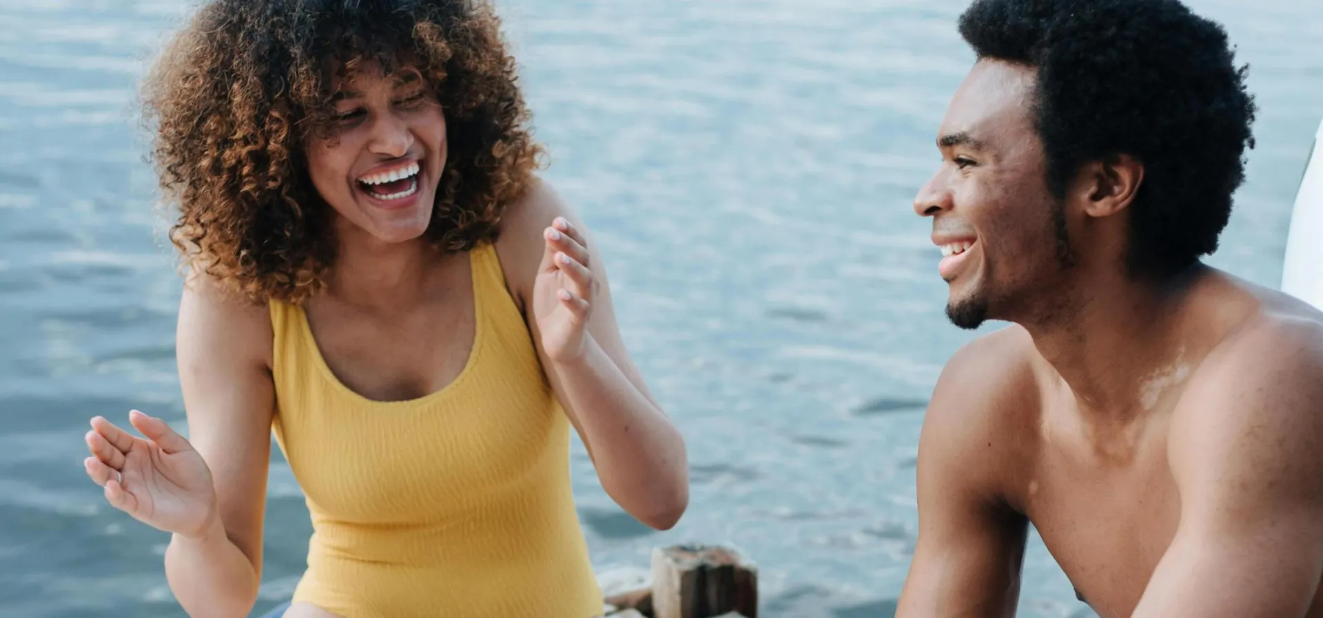 A cheerful moment by the lake featuring a couple enjoying a picnic, laughter, and sunny weather.