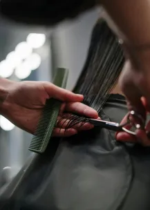 Close-up of hairstylist cutting wet hair in a salon.