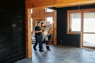 Two adults discussing home renovation in a partially constructed modern wooden interior.