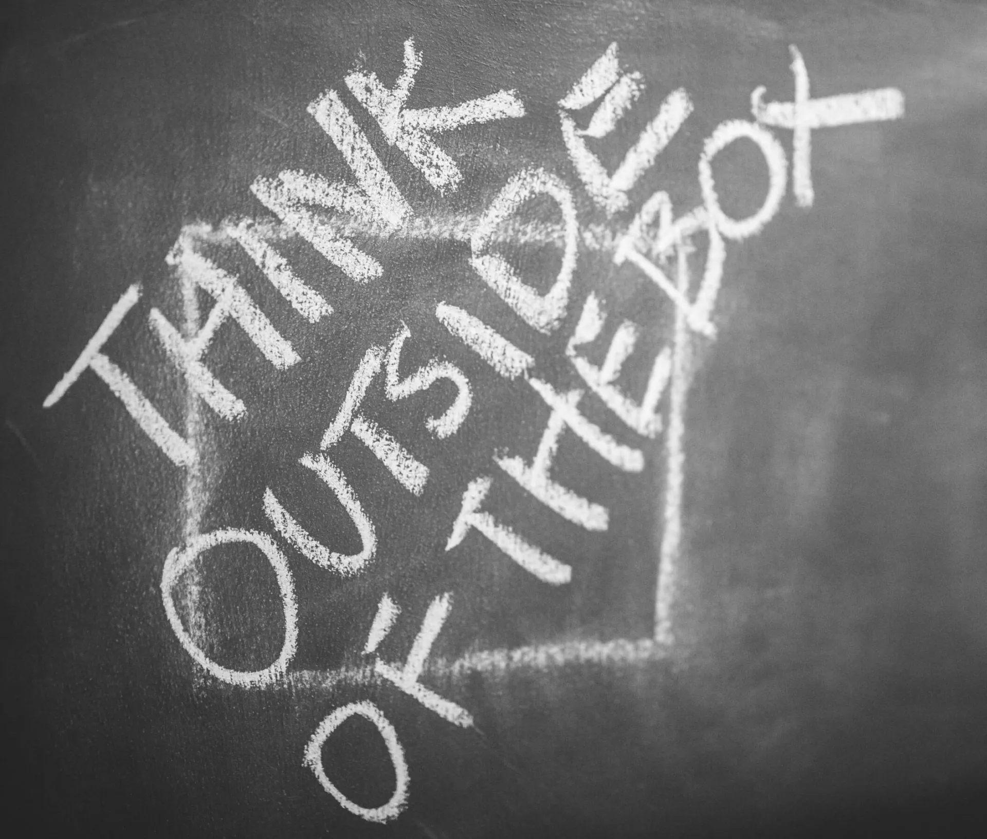 Chalkboard with 'Think Outside the Box' handwritten, inspiring creativity.