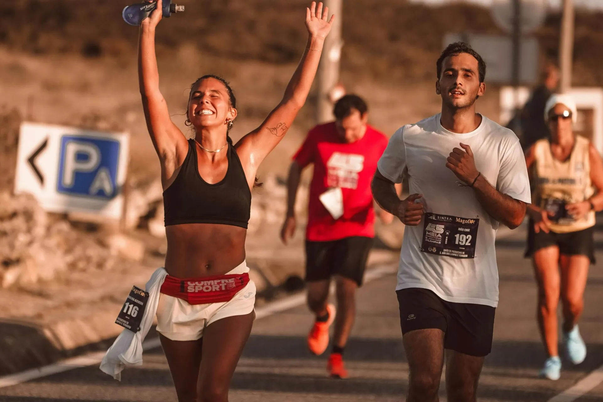 Marathon participants celebrating victory with joyful expressions on a sunny day.