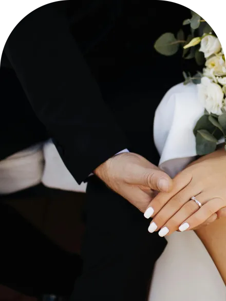 Close-up of bride and groom's hands with floral bouquet, capturing romantic essence of wedding day.