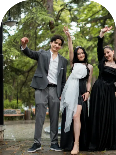 A joyful group of friends celebrating outdoors, dressed elegantly in tuxedos and gowns.
