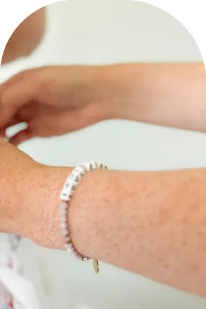 Delicate hands tying the back of a floral wedding dress, symbolizing care and elegance.