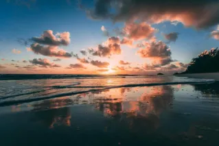 A beautiful sunrise over Kailua Beach with vibrant clouds reflected in the calm ocean water.