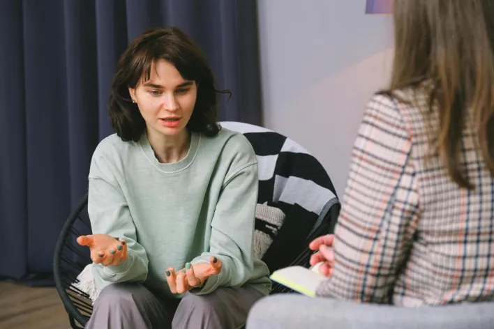Calm female sitting on armchair and giving interview to concentrated woman in light room