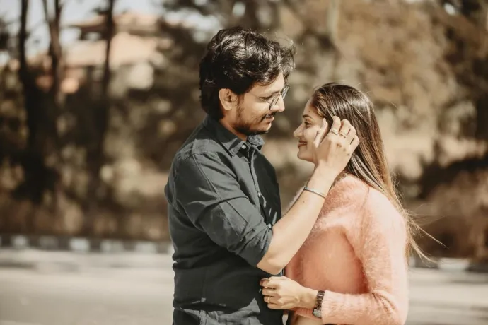 A young Indian couple embraces outdoors, showing love and happiness.