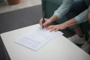 A person signing important legal documents on a table, emphasizing business and professionalism.