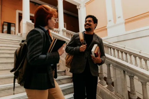 Two university students engaged in conversation on elegant marble stairs in Buenos Aires.