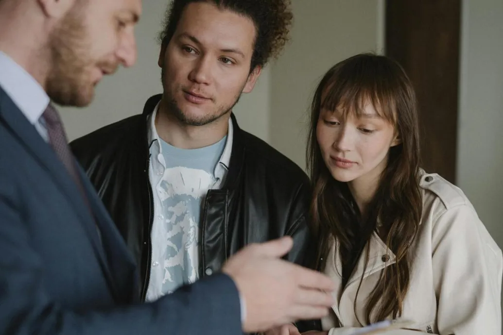 A real estate agent conversing with a potential client couple inside a modern home.