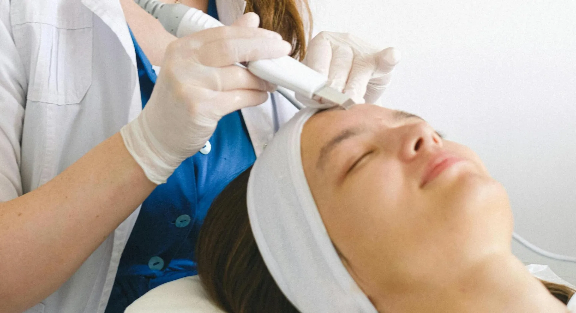 A beautician performs a facial treatment on a client in a clinic, enhancing skincare and rejuvenation.