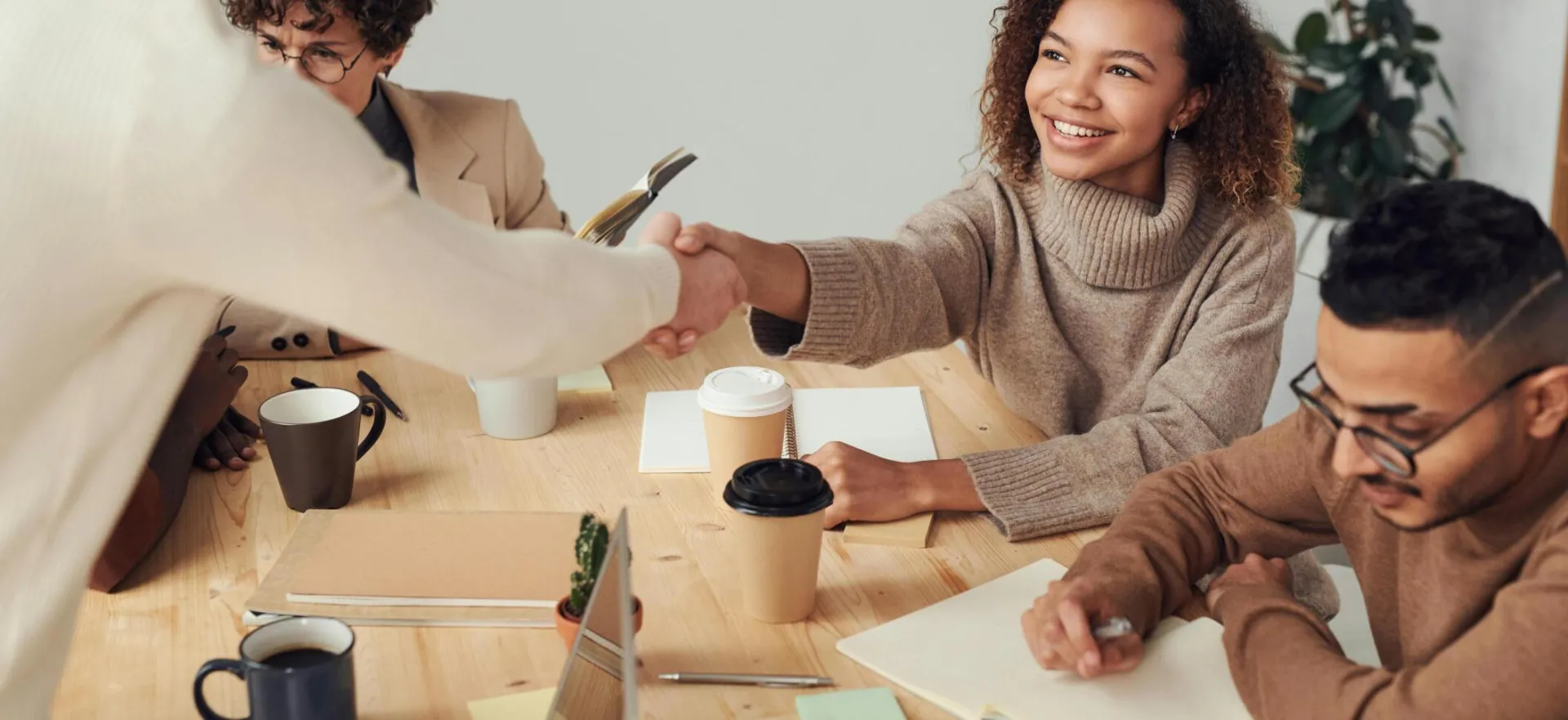 Colleagues in a positive meeting, exchanging a handshake while discussing projects.