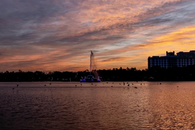 Stunning sunset view of Lake Eola fountain and city skyline with vibrant colors.