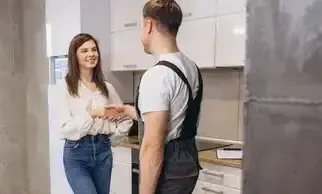Service man shaking the hand of women homeowner in her kitchen.
