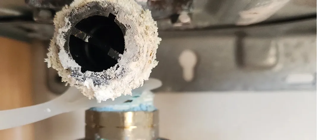 Black inline filter that is covered with calcium that is coming out from the sides. Displays dirty filter.