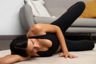 Pregnant woman doing yoga poses with a trainer in cozy indoor setting.