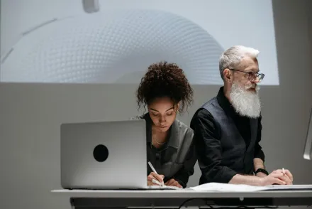 Two designers collaborating on a project with a futuristic model projection, illustrating teamwork and innovation.