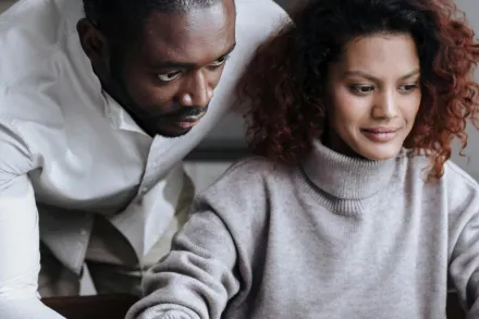 A diverse couple working together on a laptop in a cozy home setting, showcasing teamwork and technology.