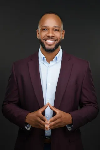 Smiling black businessman holding documents in a modern office setting.