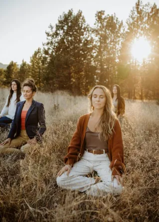 A serene outdoor meditation session with a group of women in an autumn park setting.