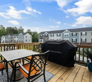 Charming wooden deck with furniture, grill, and suburban view.