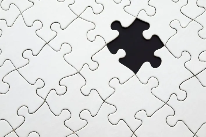 Close-up of an incomplete white puzzle with one missing piece, symbolizing challenge and strategy.