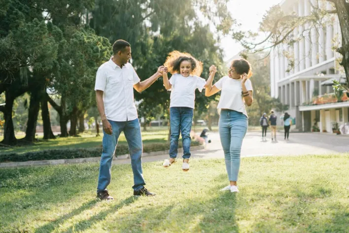 Joyful family enjoying a playful day at the park, embracing love and togetherness under the summer sun.