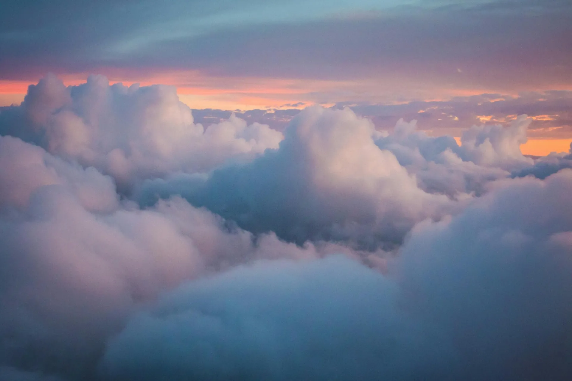 Closeup of multiracial hands holding, symbolizing unity and equality against a serene sky.