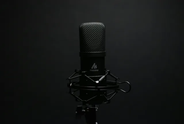 Studio microphone with shock mount on a dark backdrop, perfect for audio recording setups.