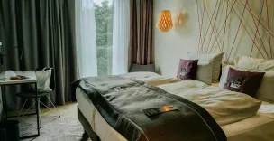A modern and cozy hotel room featuring a double bed, stylish lighting, and a workspace.