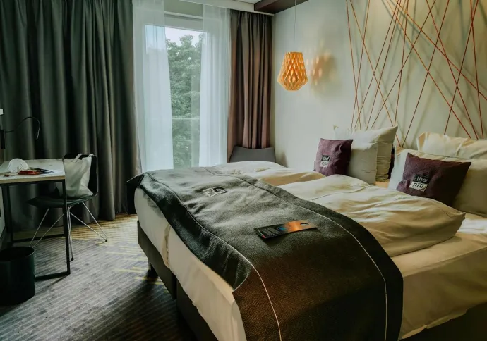 A modern and cozy hotel room featuring a double bed, stylish lighting, and a workspace.