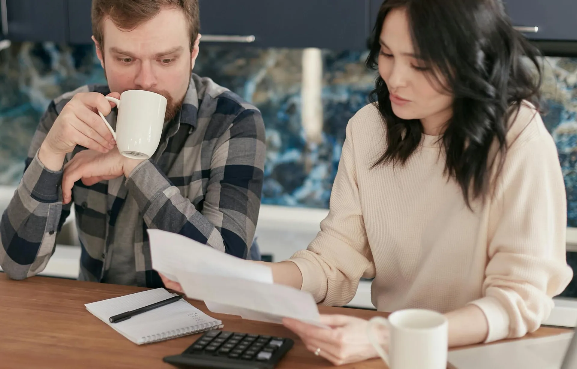 A couple reviewing bills using a calculator and paperwork, symbolizing financial planning at home.