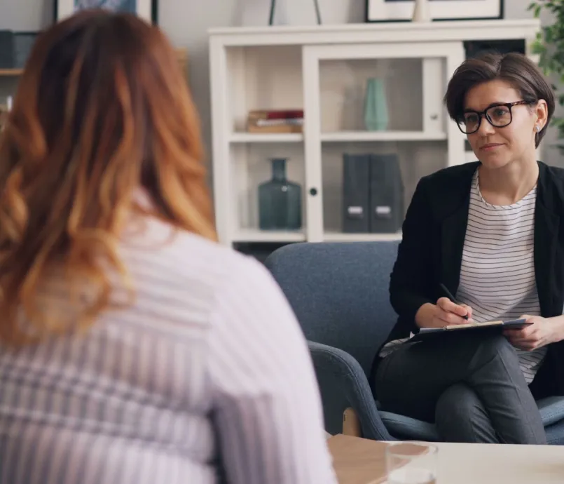 A therapist and patient having a counseling session in a modern office sitting area.