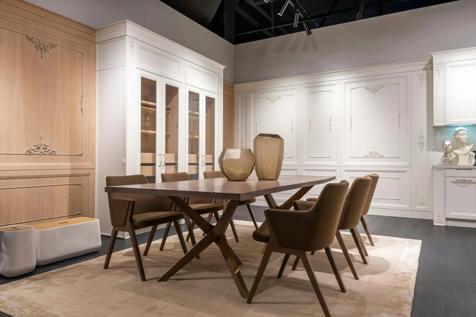 Modern stylish dining room with white cupboards and decorative vases on dining table in contemporary apartment