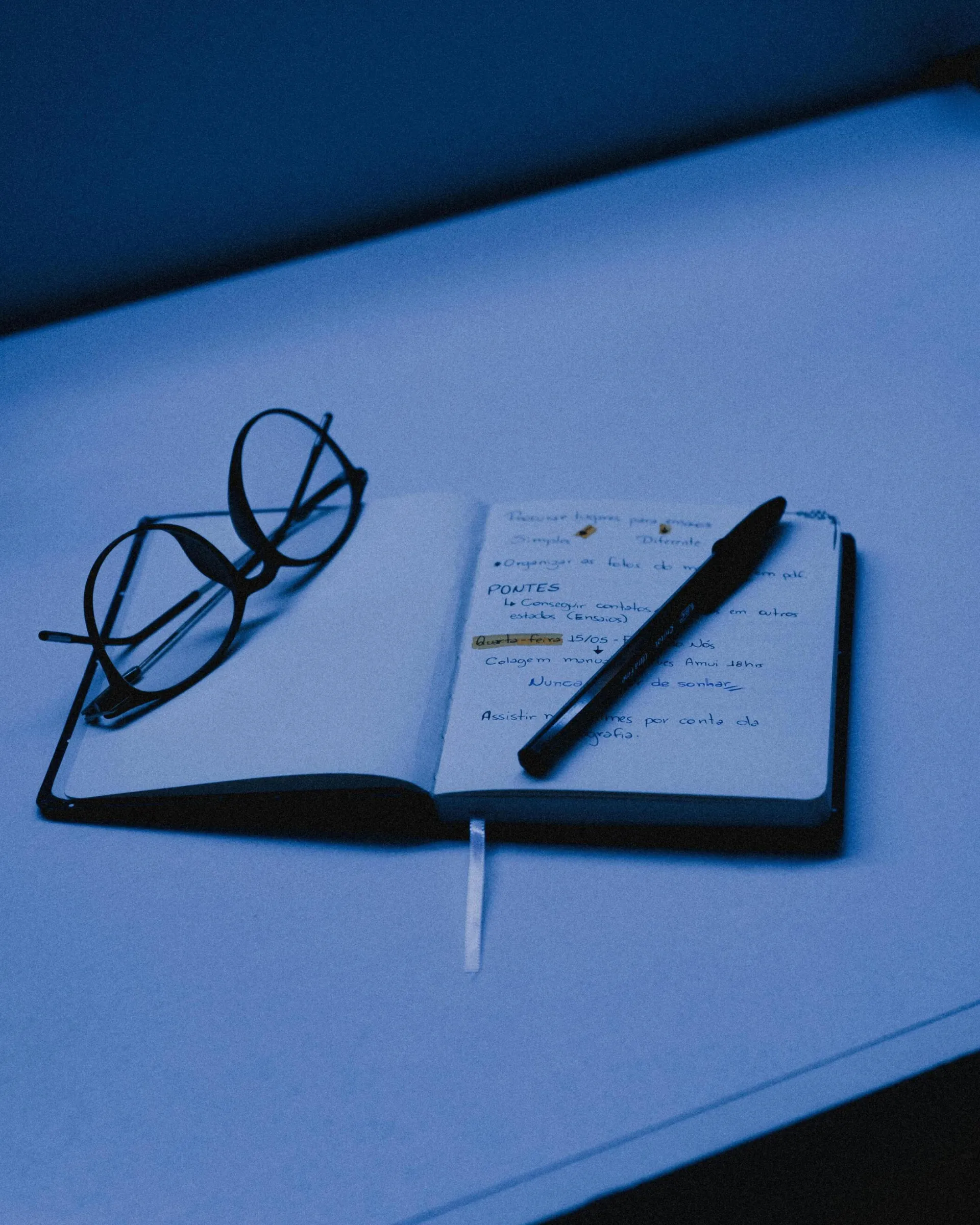 An open notebook with a pen and eyeglasses on a desk, capturing the essence of studying or planning.