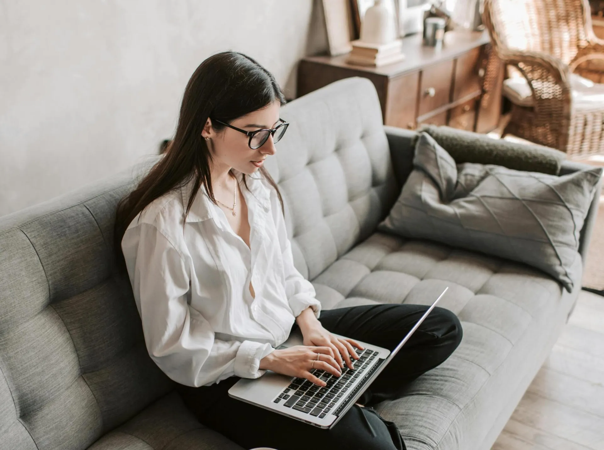 Woman in a cozy home setting working on a laptop for remote work and relaxation.