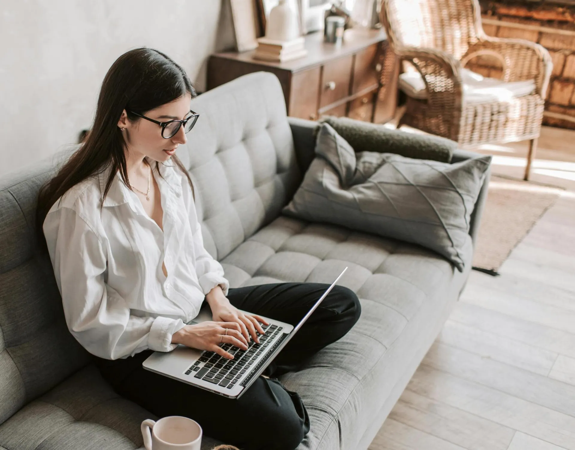 Woman in a cozy home setting working on a laptop for remote work and relaxation.