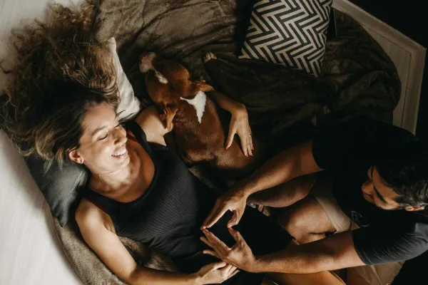 Relaxing indoor moment with a happy couple and their dog in a cozy setting.