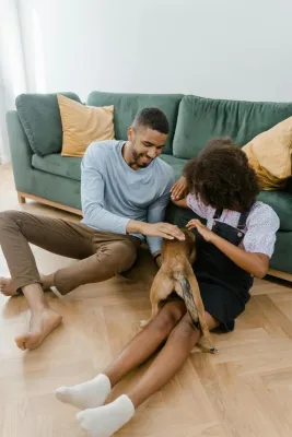 A joyful moment as a man and girl bond with their pet dog indoors.