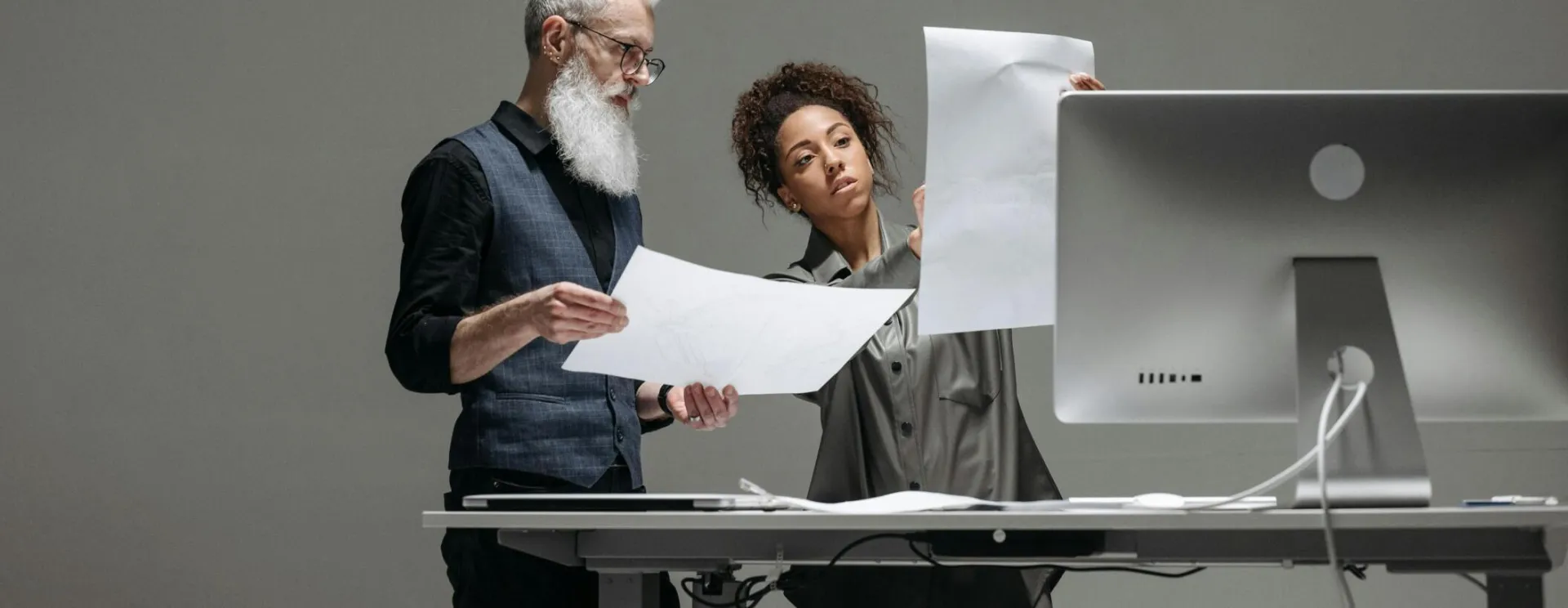 Two professionals collaborate on project plans at a computer workstation.