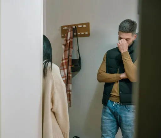 A man and woman argue in a domestic setting, showcasing tension and sadness.