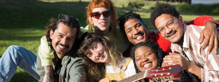 A diverse group of friends enjoying a sunny day outdoors with music and laughter.