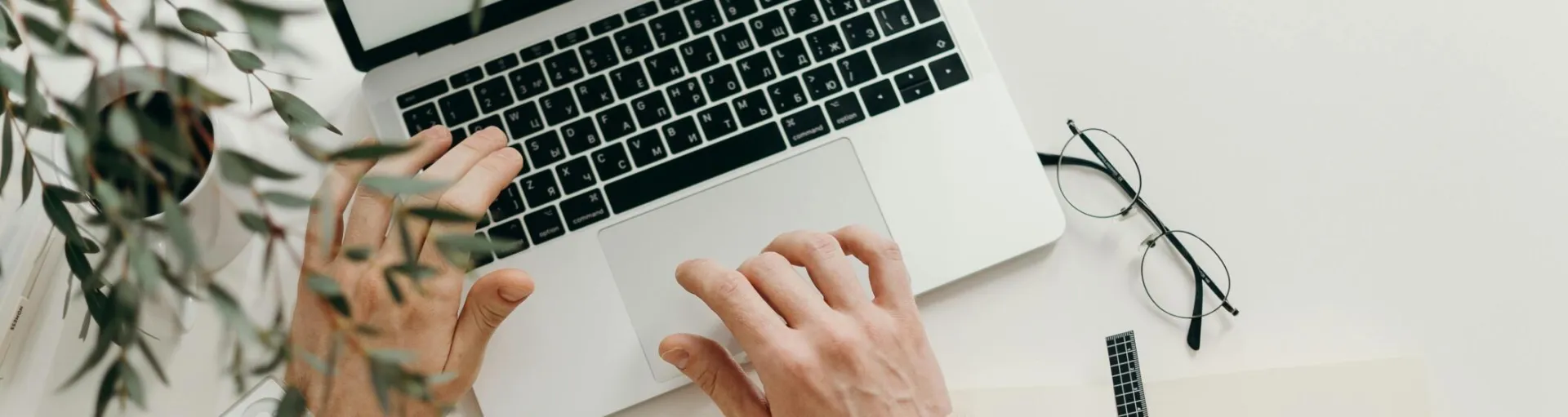 An overhead view of a person working on a laptop in a minimalist home office setting.