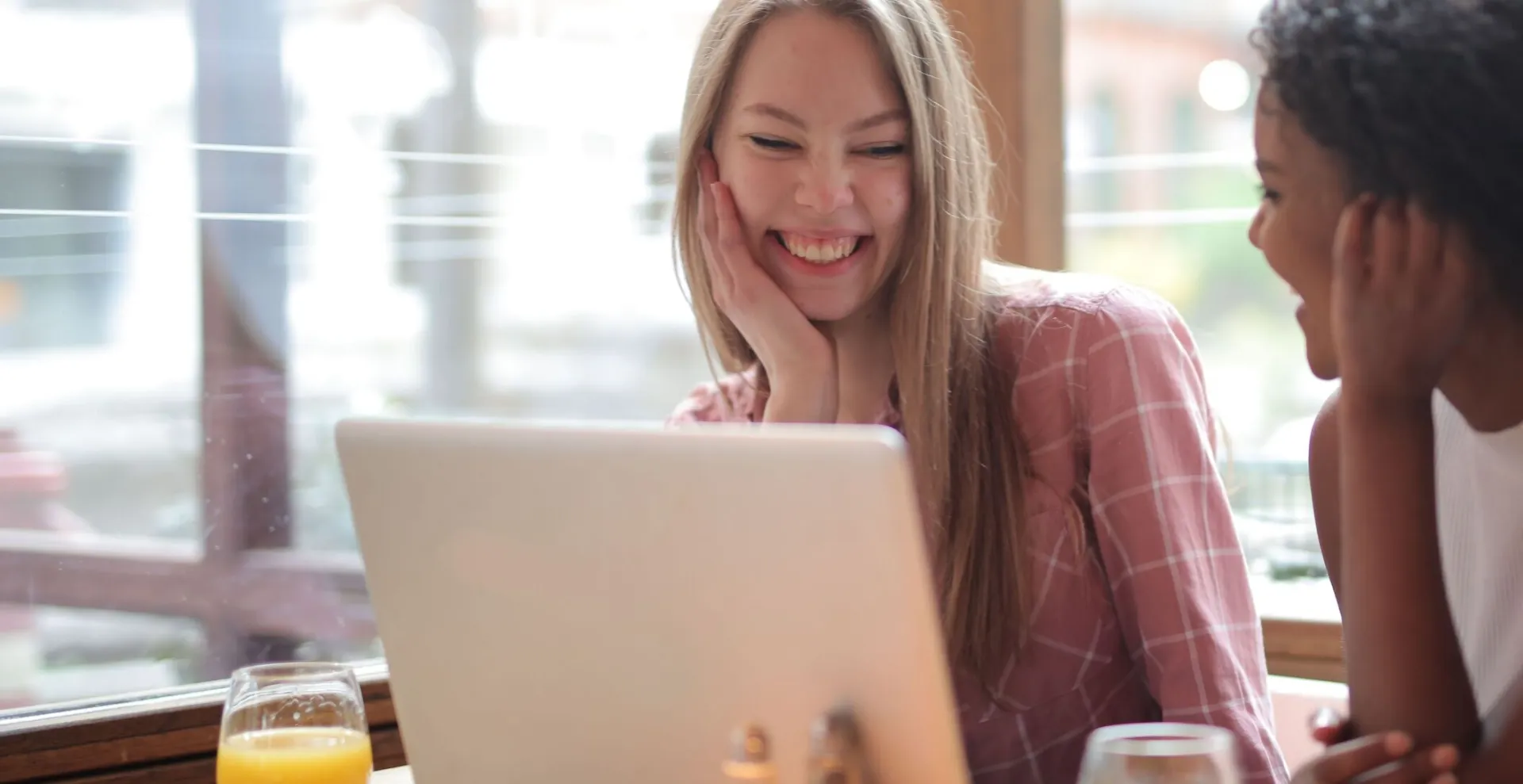 Two women chatting and smiling over breakfast in a cozy café setting.