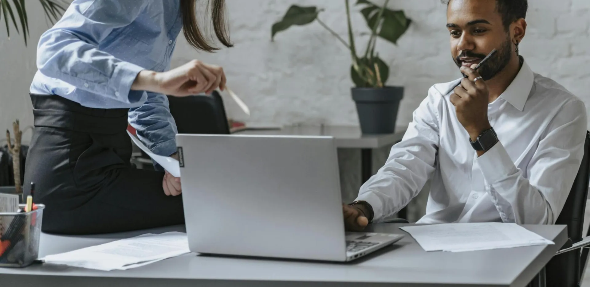 A group of professionals collaborating in a modern office setting, engaging with technology and teamwork.